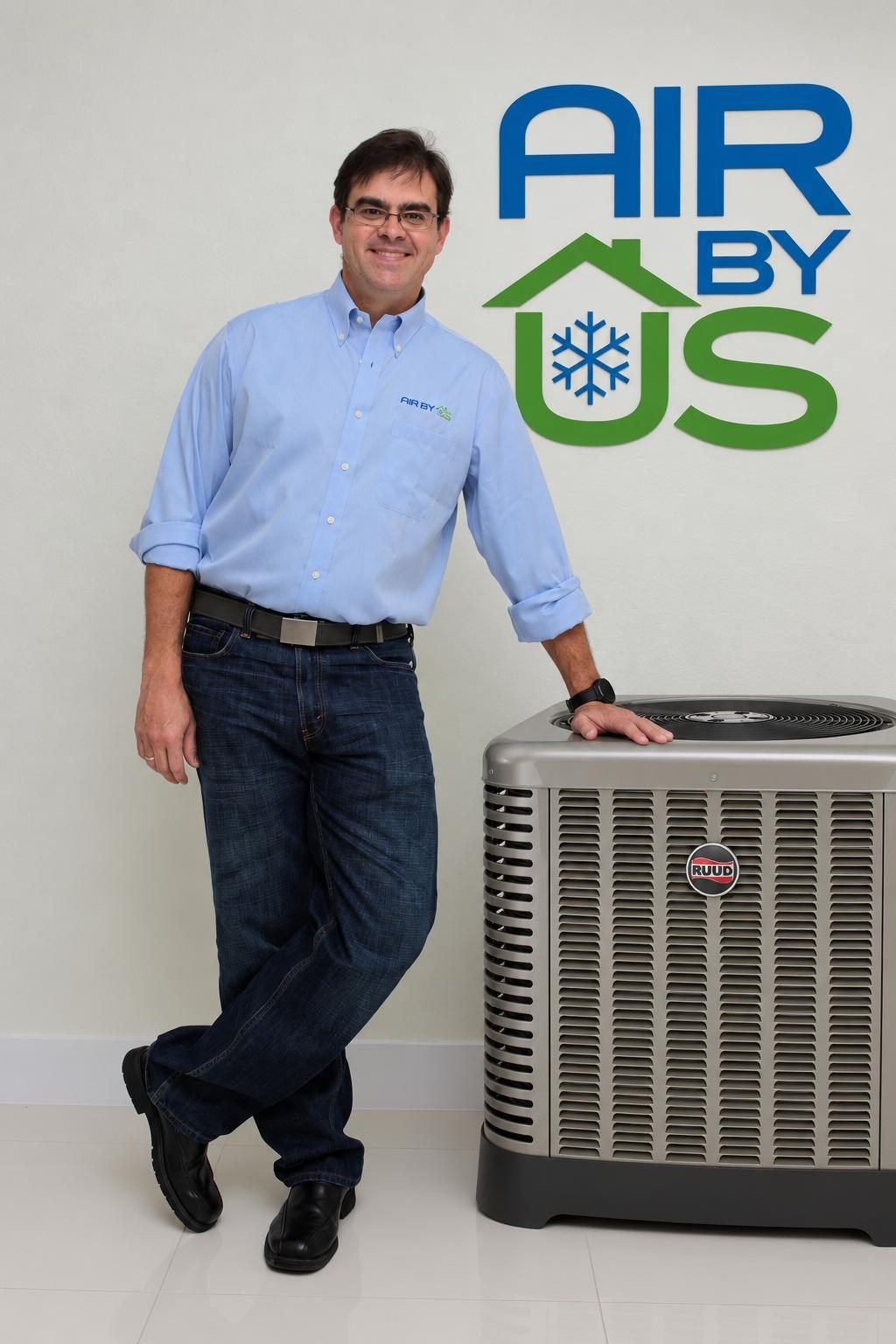 Javier Budejen of Air By Us standing beside an outdoor condenser unit